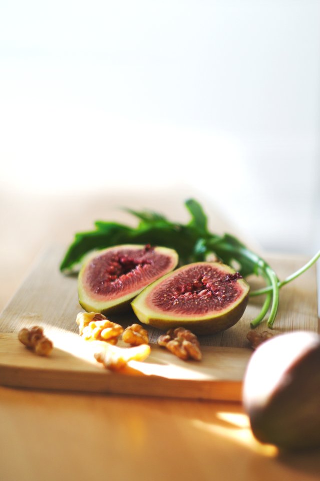 sliced in half oval green fruit above wooden chopping board