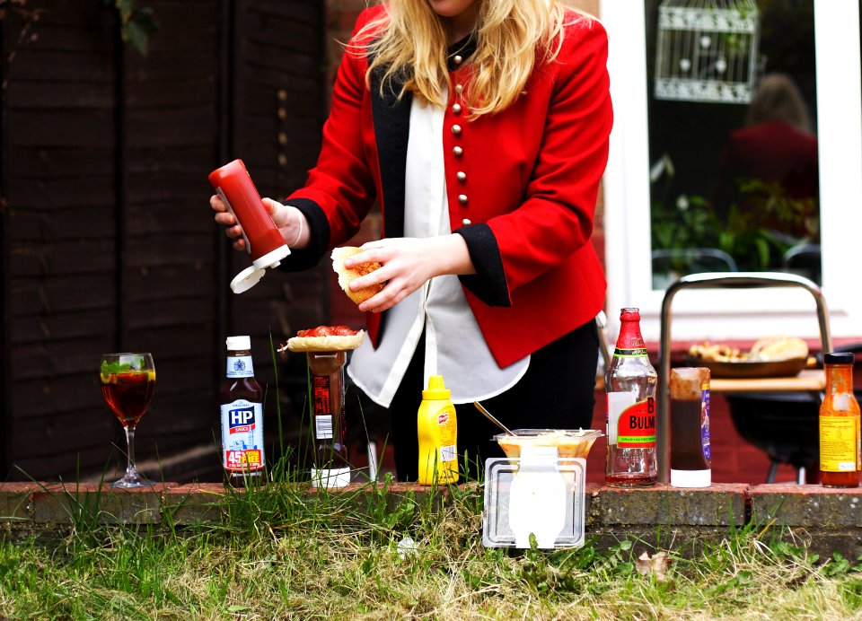 woman putting red sauce on hamburger