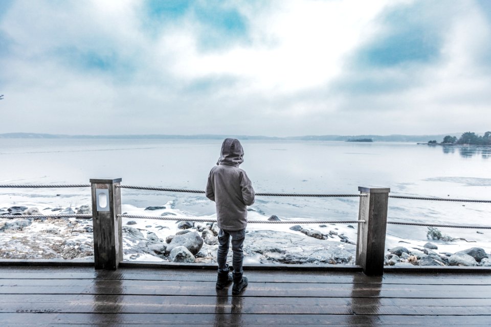 child standing infront of seashore on brown platform