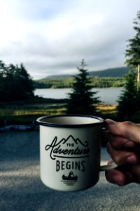 person holding cup with body of water background photo