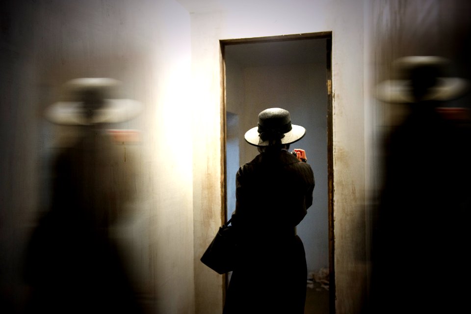 person wearing hat carrying bag while standing in front of door