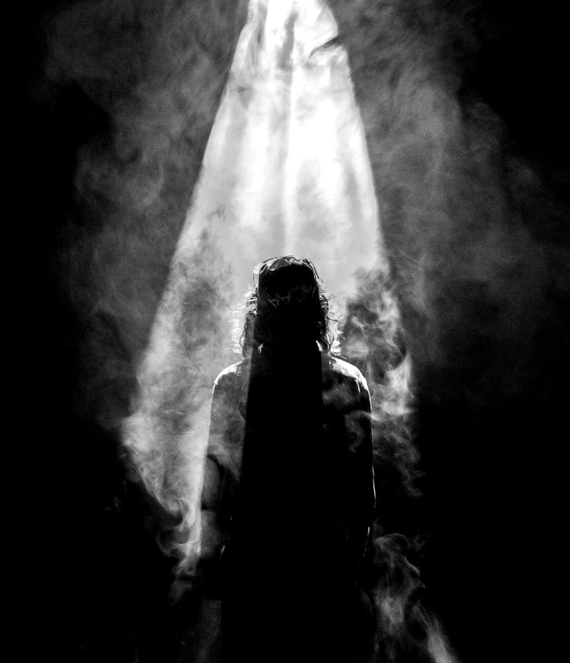 photograph of person facing opposite in smoky spotlight