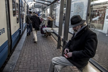 man sitting on waiting bench in train station photo