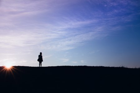 person's silhouette standing on field photo
