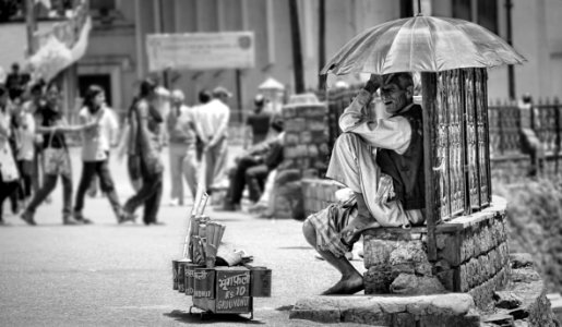 grayscale photo of man sitting on concrete bench photo