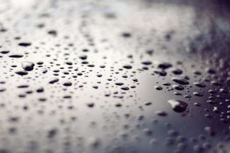 macro photography of water drops on black glass surface photo