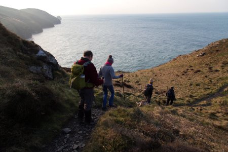 four hiking on mountain viewing blue sea during daytime