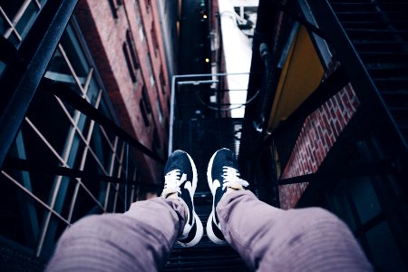 person wearing pair of black Nike shoes sitting on metal frame