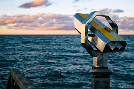 gray metal telescope near body of water