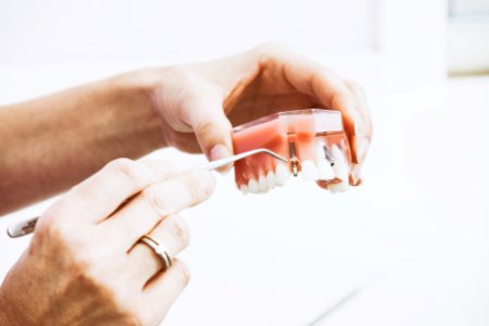 person wearing silver-colored ring while holding denture photo