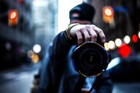 selective focus photography of man holding a camera at the street photo