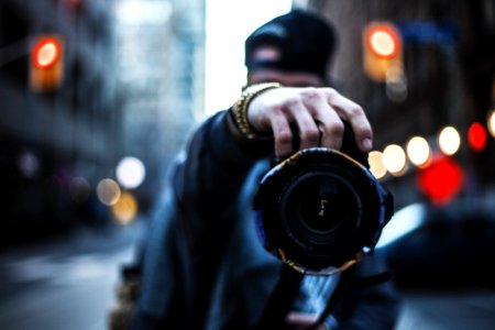 selective focus photography of man holding a camera at the street