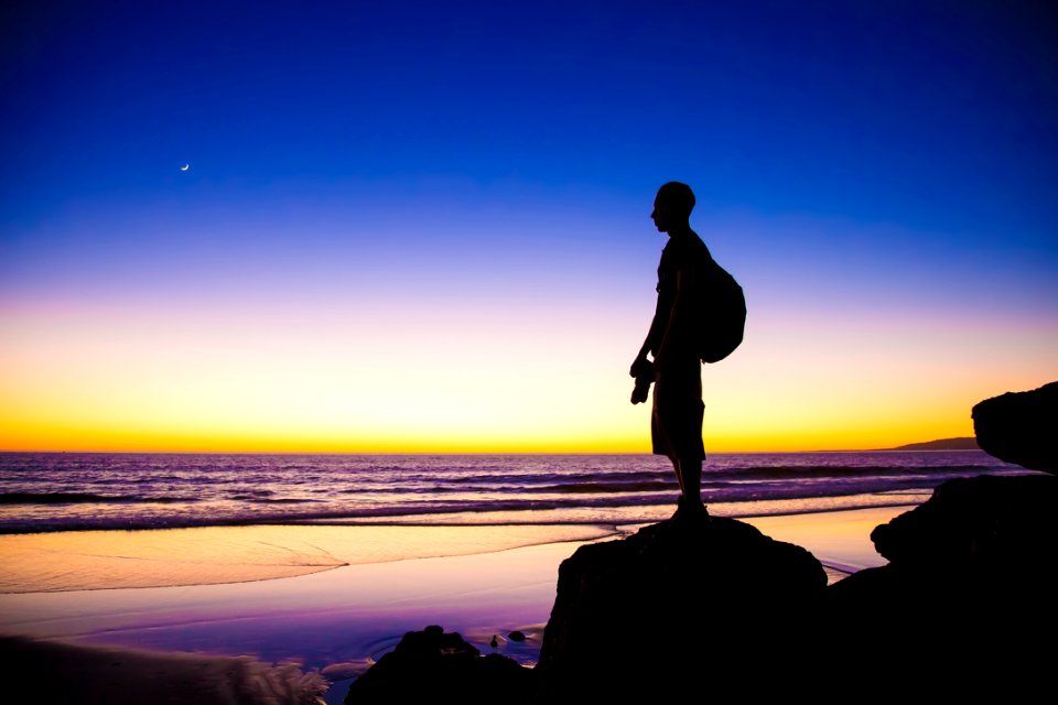 silhouette of man standing on cliff