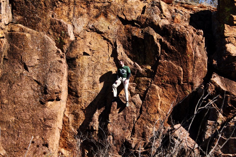 man in white shirt climbing brown rock mountain during daytime