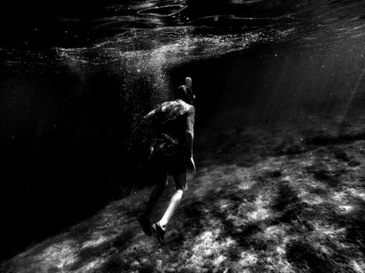 grayscale photography of man swimming underwater photo