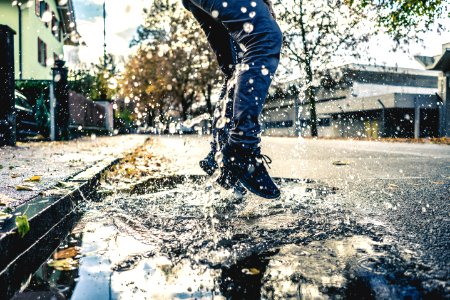person making splash on water puddle on road photo