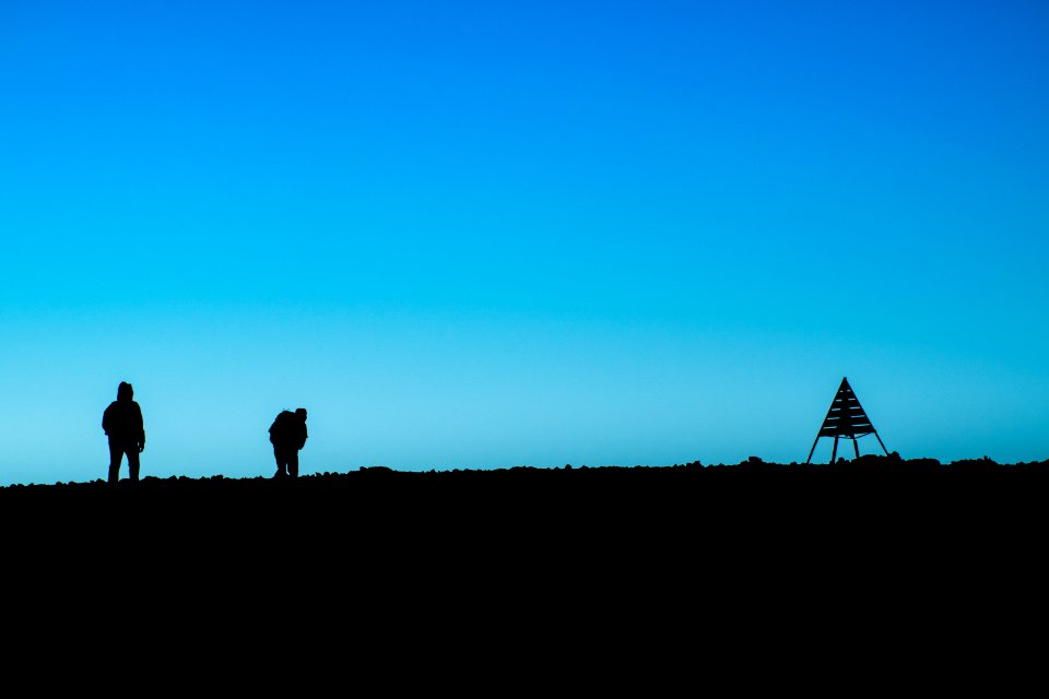 silhouette of two person standing on ground near tent at daytime