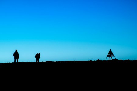 silhouette of two person standing on ground near tent at daytime photo