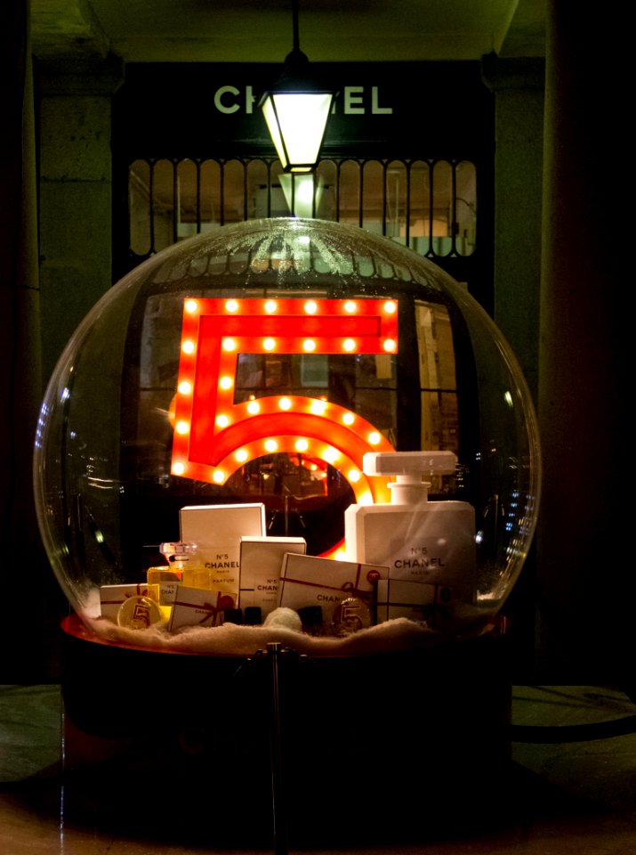 A large glass ball with the number 5, full of Chanel products in front of their storefront.