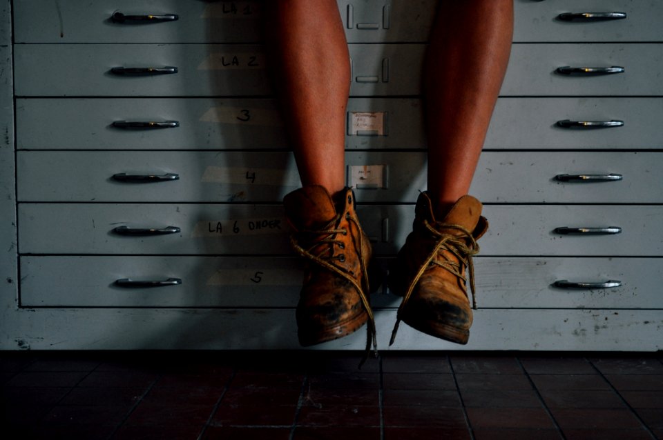 person wearing brown work boots on cabinet