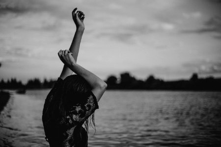 grayscale photo of woman stretching body front of body of water photo