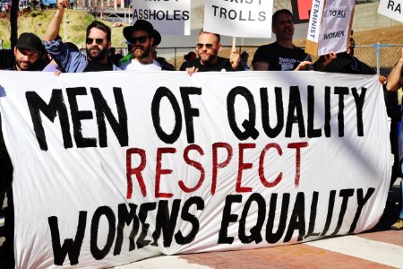 men holding white, black, and red Men of quality respect womens equality banner on road photo