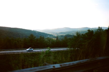 car riding on road between trees near mountain range photo