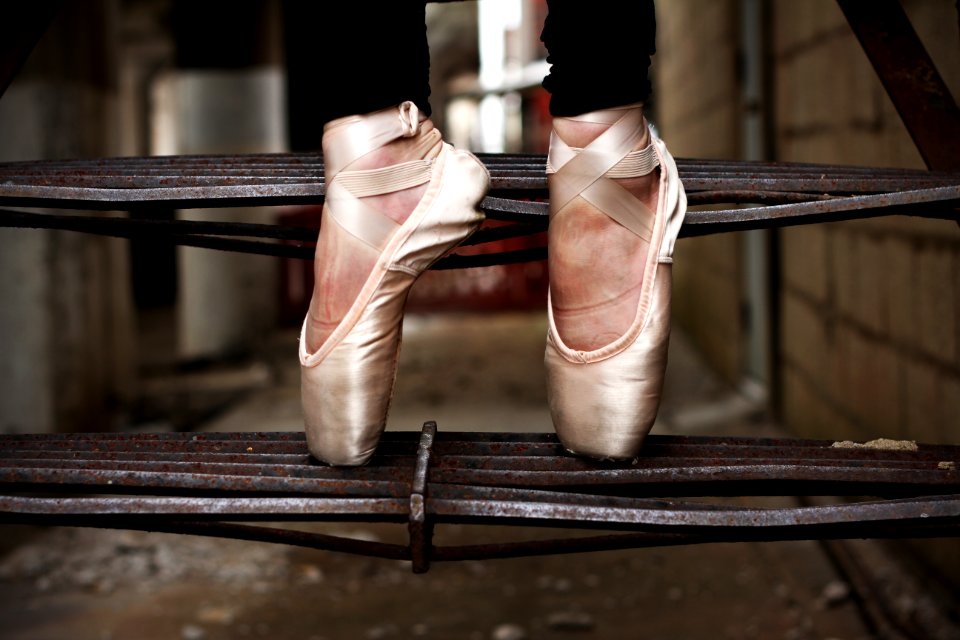A woman standing on her tippy-toes in dance shoes on an outdoor staircase.