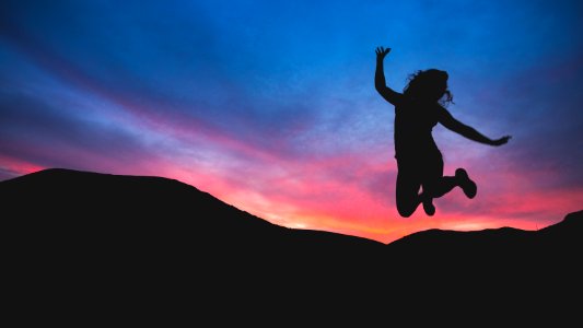 silhouette of person jumping during dawn photo