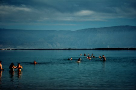 group of people in body of water near green mountain photo