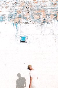 man standing facing white brick wall photo