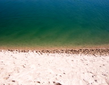 white sand near green calm body of water at daytime photo