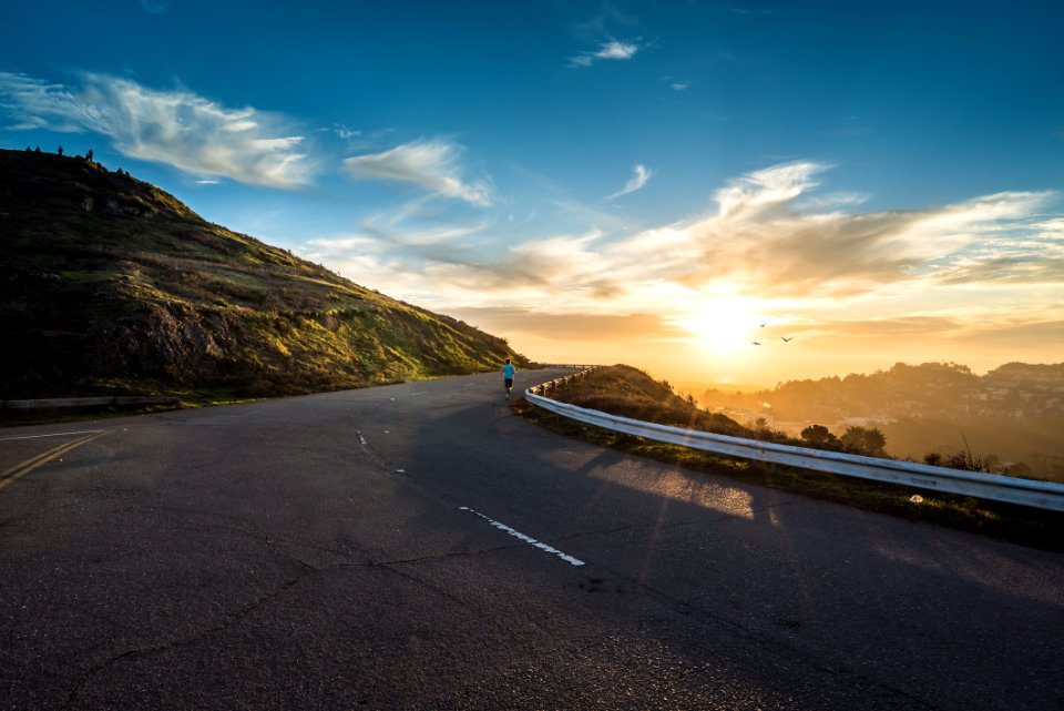 person running on road street cliff during golden hour