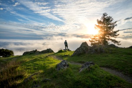 person standing on top of the mountain under cloudy sky photo