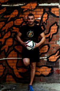 man leaning on wall holding velleyball