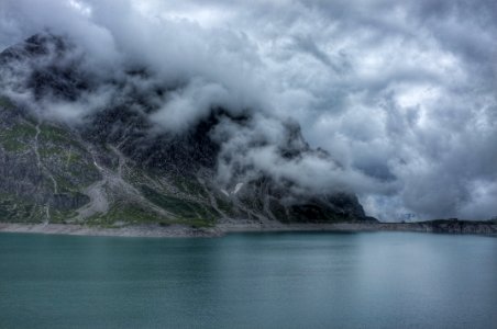 body of water beside mountain covered with fog photo