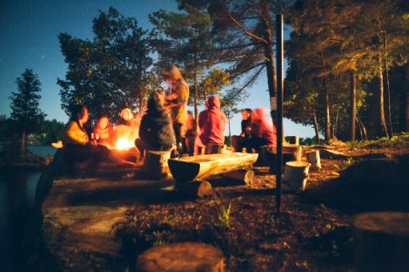 group of people near bonfire near trees during nighttime photo