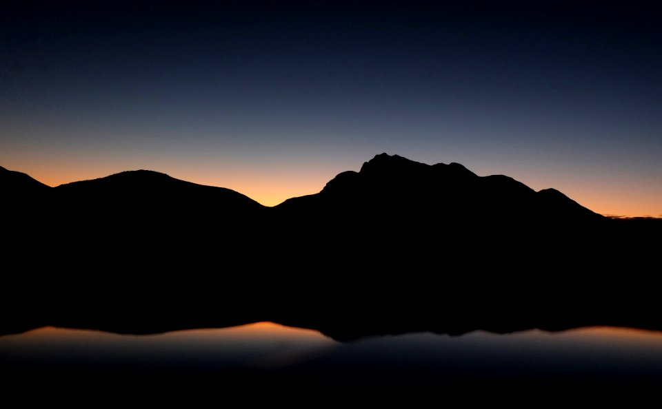 silhouette photography of mountain near body of water