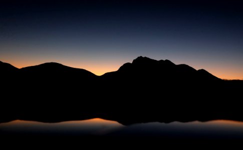 silhouette photography of mountain near body of water photo
