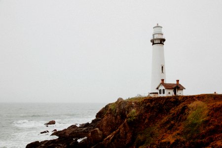 white lighthouse on rocky cliff photo