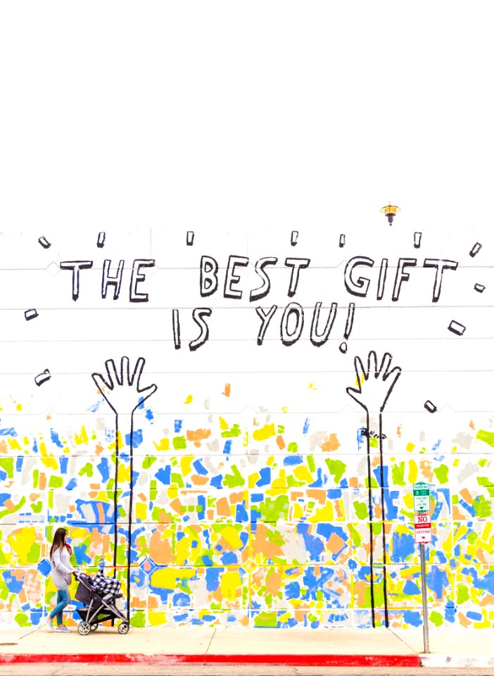 woman walking beside wall with the best gift is you graffiti