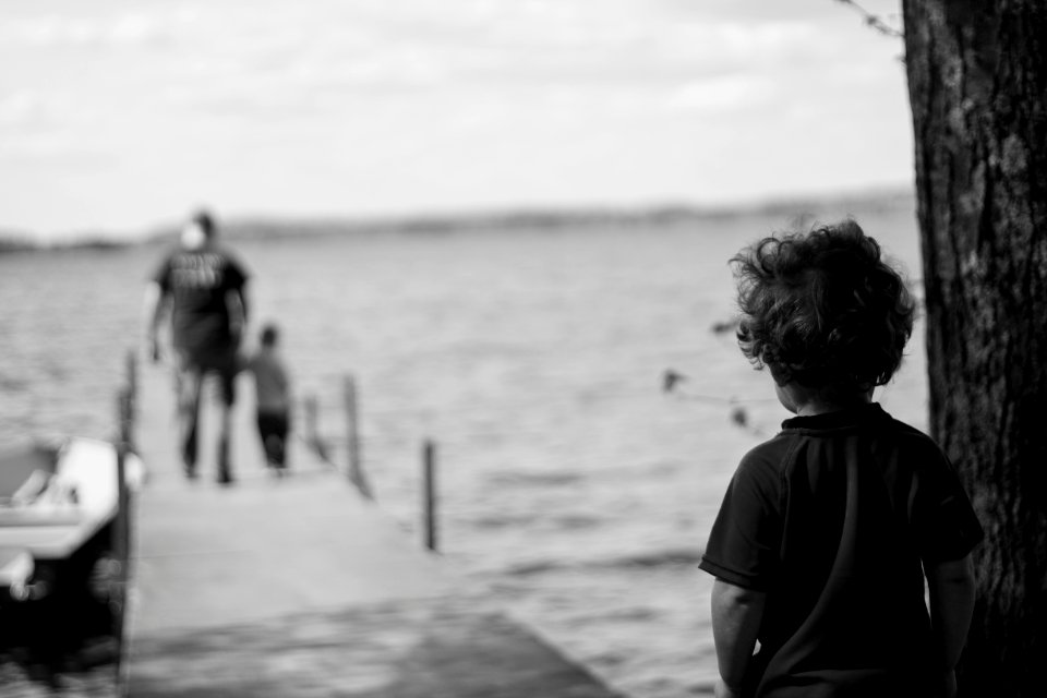 grayscale photography of child beside tree