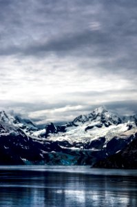 calm lake water near snowy mountain peak under cloudy skies