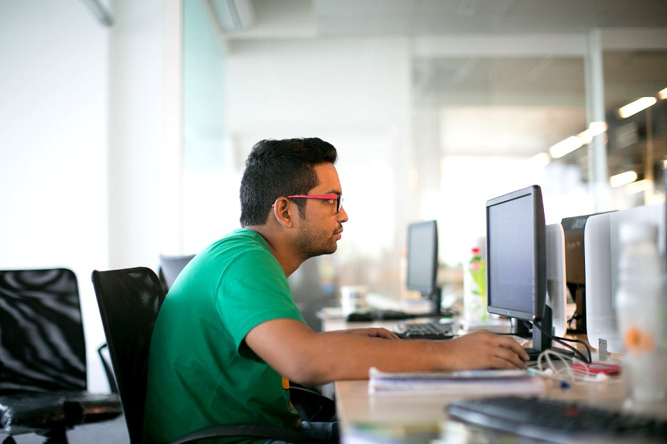 man in green crew neck t-shirt sitting on black office rolling chair