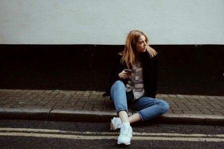 woman sitting on floor while holding smartphone photo