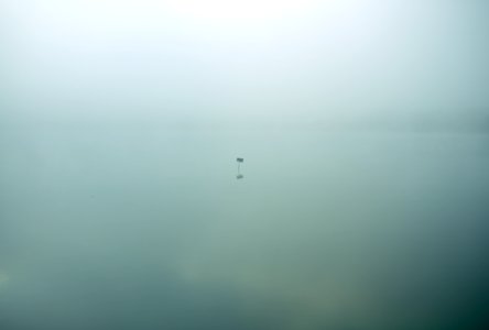 Single isolated sign sits in eerie still waters covered in clouds