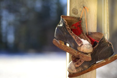 pair of black-and-brown ice skates hanging on brown wooden post photo