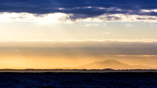 silhouette of road and mountain under gray clouds at golden hour photo