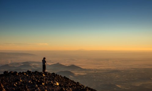 man standing on cliff during golden hour photo