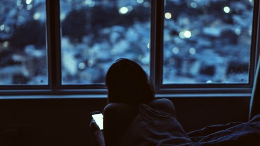 woman holding phone near window during daytime photo